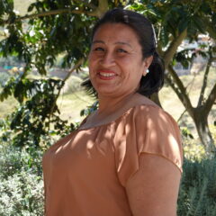Woman standing under trees smiling.